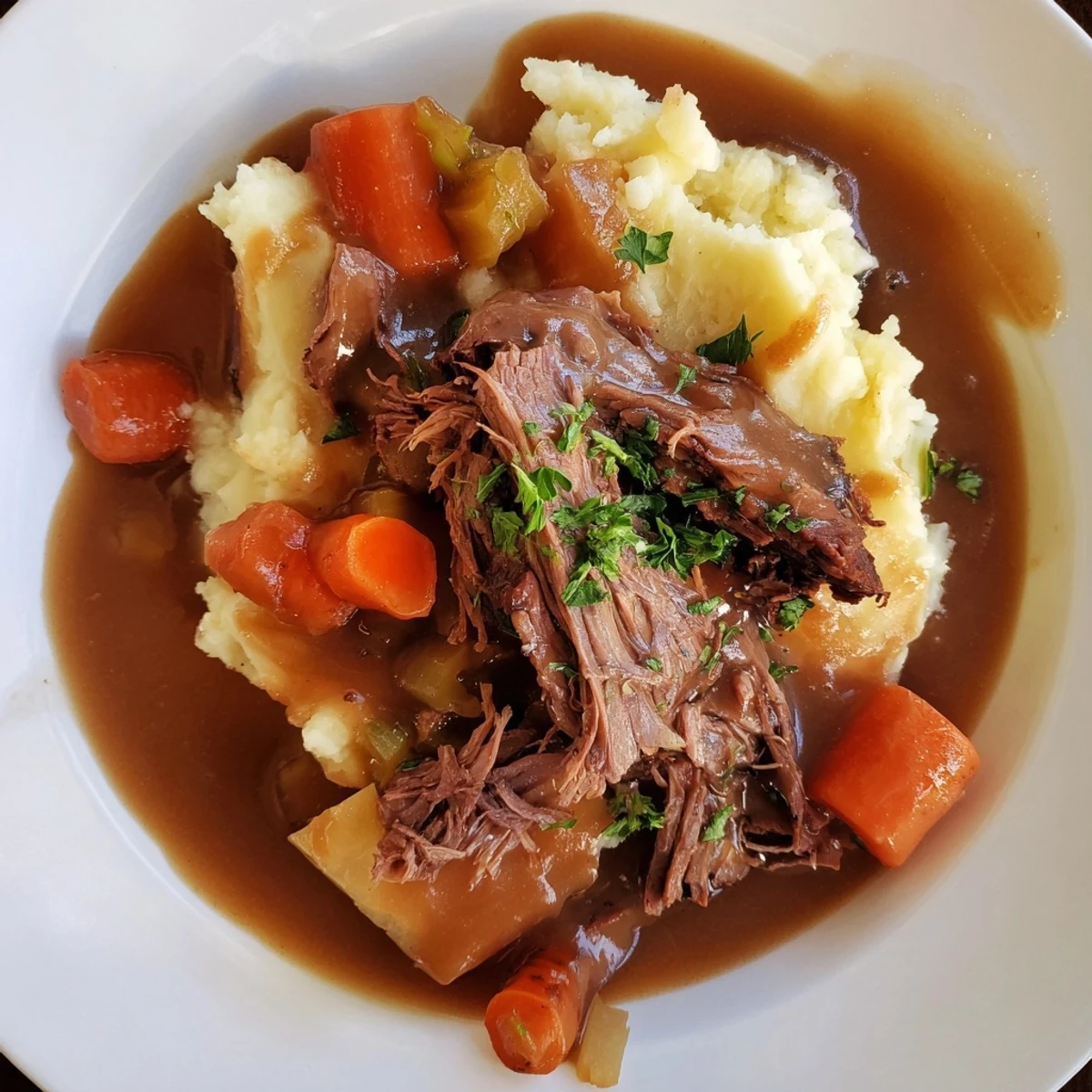 A steaming bowl of Slow Cooker Pot Roast with rich gravy and creamy mashed potatoes.