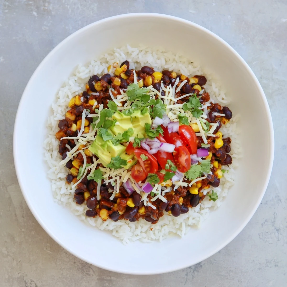 Enjoy a colorful serving of Rice, Bean, and Corn Burrito Bowls with fresh cilantro and lime wedges.