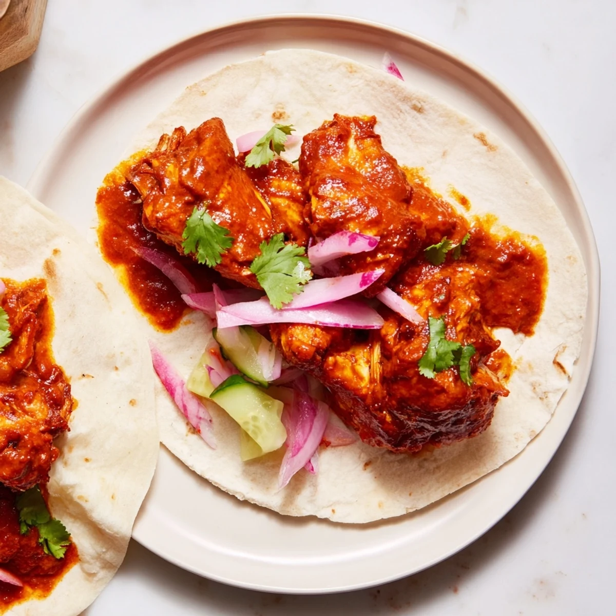 A delicious close-up of tender chicken tikka masala encased in warm tortillas with vibrant toppings.