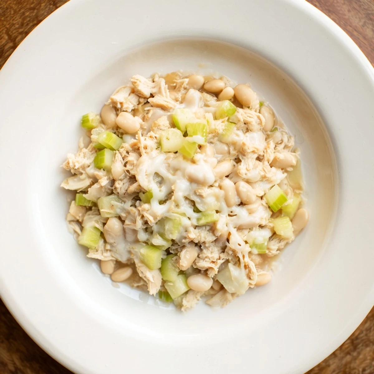 Steaming bowl of 35-Minute White Cheddar Apple Chicken Chili, topped with extra shredded cheddar cheese.