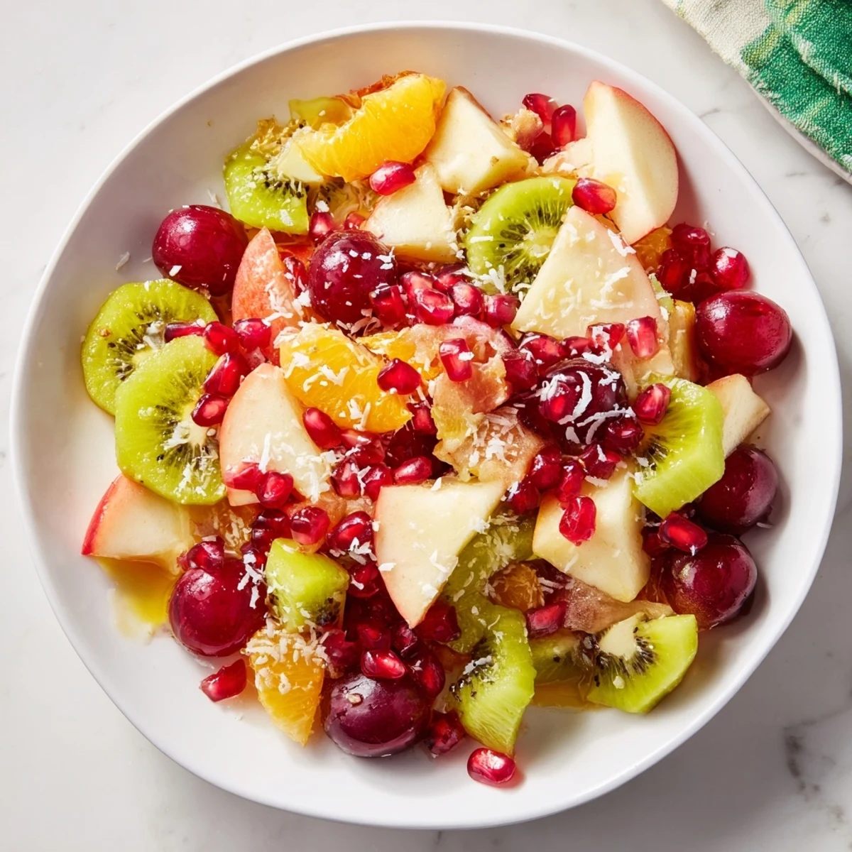 Snowflake Fruit Medley glistens— vibrant red grapes, orange segments, and sweet kiwi slices.