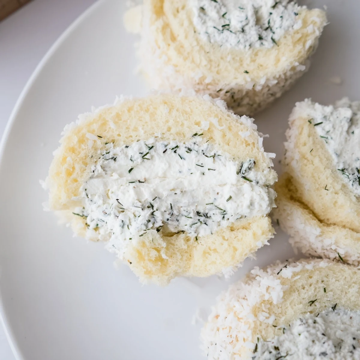 Plump, round Snowball Tea Sandwich Bites with visible creamy filling, dusted with white coconut.