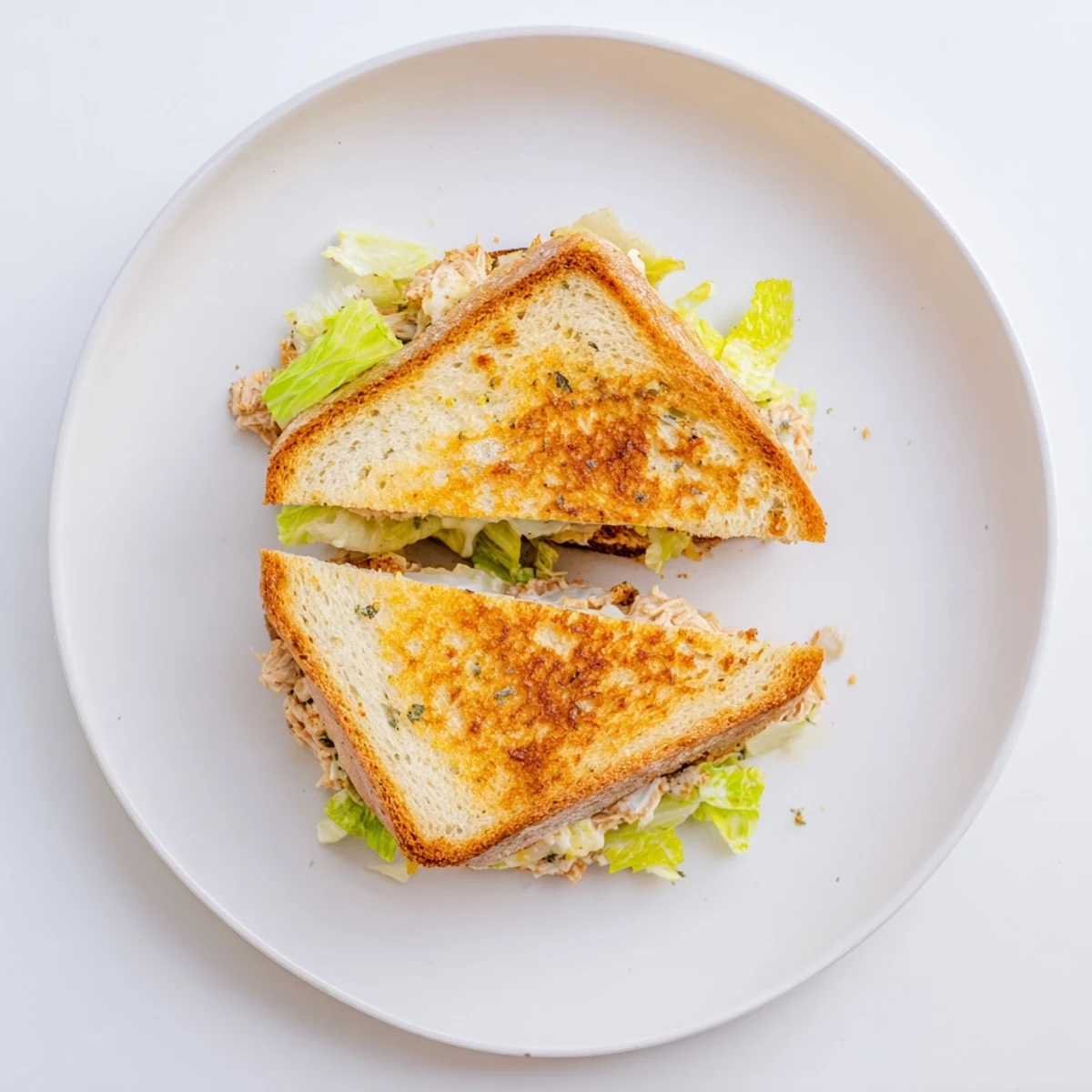 A close-up of a sliced Buffalo Chicken Caesar Grilled Cheese reveals layers of tender buffalo chicken, crisp romaine lettuce, and gooey cheese.  