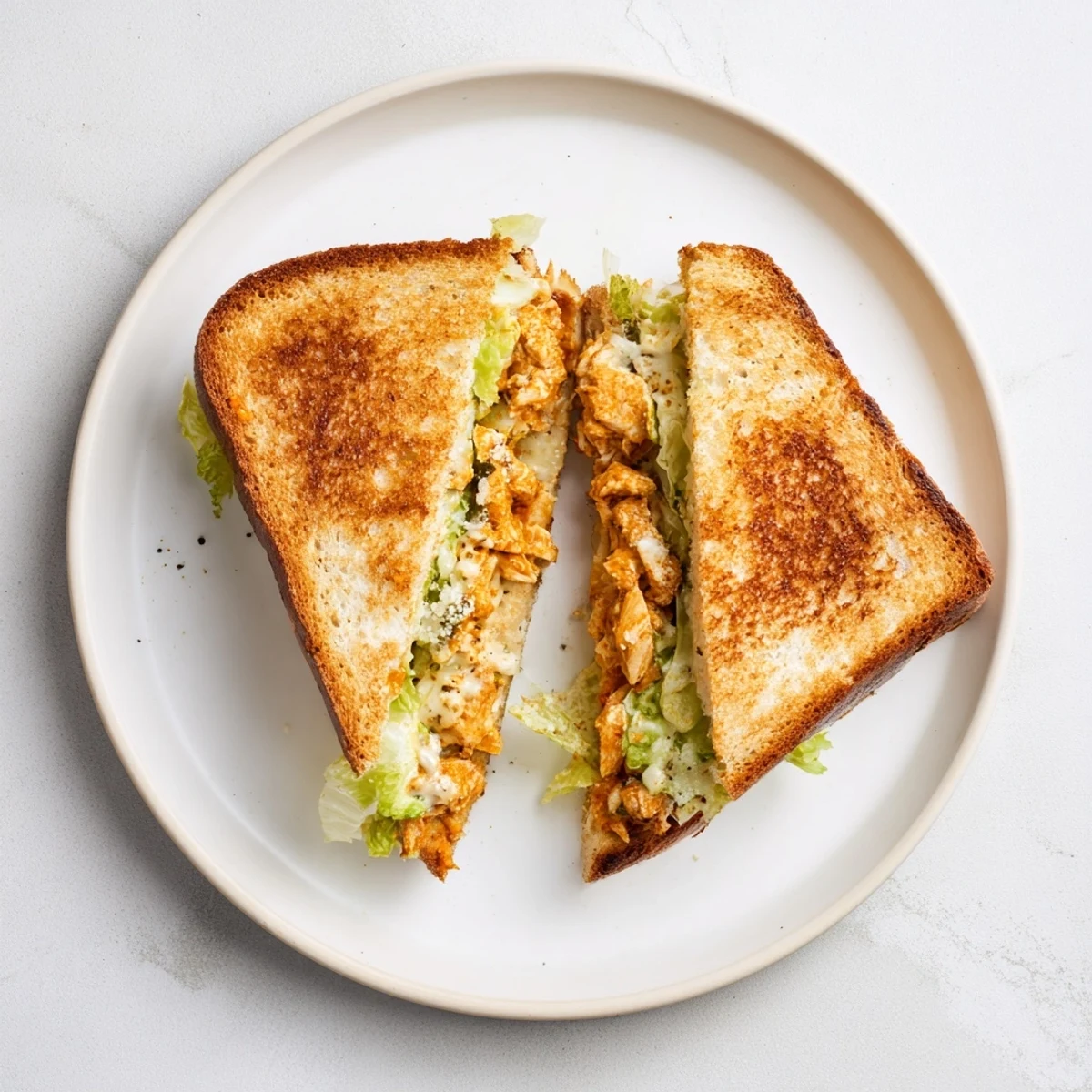 Golden-brown grilled cheese sandwiches stuffed with spicy buffalo chicken, creamy Caesar dressing, and melted provolone on rustic sourdough.  