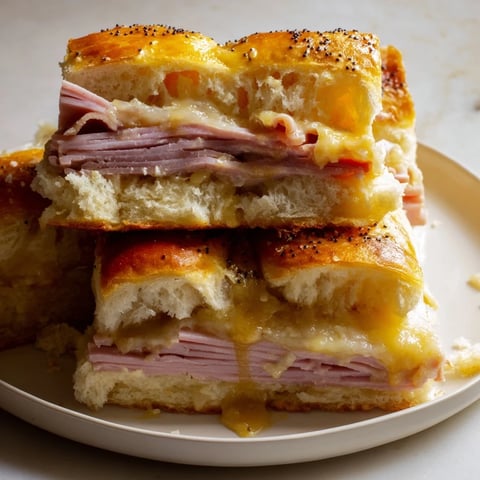 Golden-brown Budget-Friendly Ham & Cheese Sliders, showcasing layers of melty cheese and savory ham.