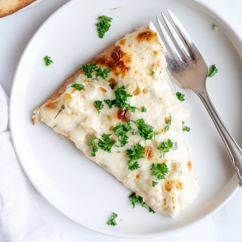 A close-up of Creamy Garlic White Pizza with golden, bubbling mozzarella and a crisp, brushed crust.