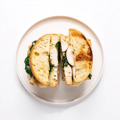 Golden-brown grilled chicken spinach panini, with melty mozzarella and fresh spinach pressed between crusty Italian bread.