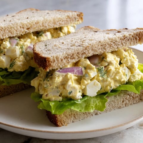 Golden egg salad sandwich filling, flecked with celery and onion, ready to eat.
