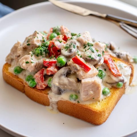 Comforting Chicken à la King dish garnished with parsley atop golden brown toast slices.  