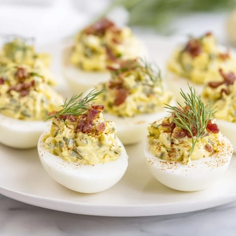Delicious loaded deviled eggs, showcasing bacon, dill, and creamy filling, perfect appetizer.