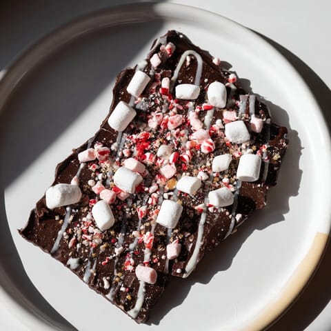 Festive Hot Chocolate Bomb Bark, featuring melted chocolate and sprinkled with mini marshmallows for holiday gifts.
