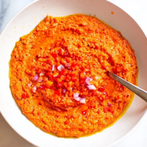 A close-up view of the fiery Volcanic Lava Spicy Dip, ready to be scooped up with crunchy pita chips.