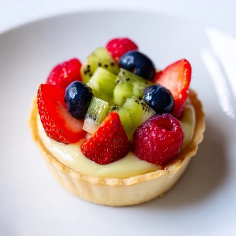 A visually stunning circle arrangement of fresh fruit topping lovely mini fruit tartlets, ready to enjoy.
