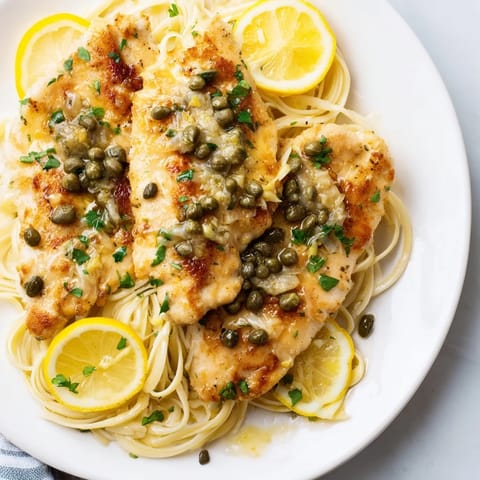 Close-up of Quick Chicken Piccata Pasta, showcasing tender chicken over perfectly cooked pasta and vibrant sauce.