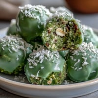 Matcha coconut energy balls with oats on a white plate, rolled in shredded coconut for extra texture and flavor.  