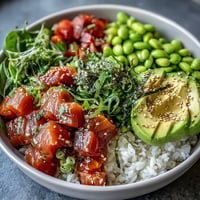 Salmon Poke Bowl: colorful marinated fish, creamy avocado, vibrant vegetables over rice.